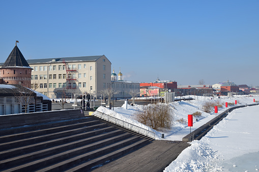 Tula, Russia - March 2, 2024: People walking on the Kazan embankment of the Upa River and the Tula Kremlin tower. Winter morning. Tula, Russia