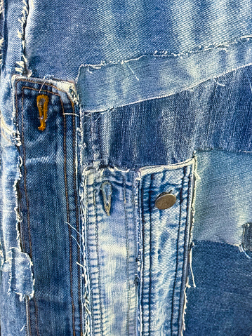Stock photo showing close-up view of a pair of blue denim jeans sporting a customised design of bleached patchwork, to make them look like expensive designer jeans.