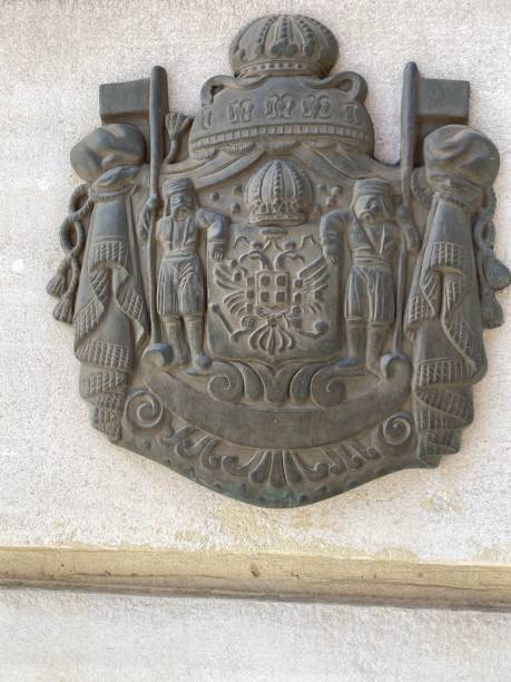 istock Antique metal crest with crown, flags, soldiers on wall 2075877022
