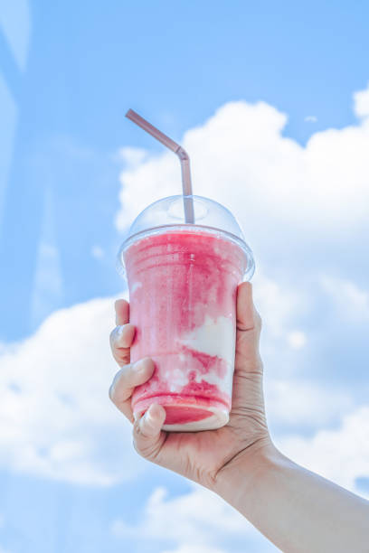 ピンクのイチゴのスムージーが入ったプラスチックのグラスを持つ手 - blueberry smoothie milk shake drink ストックフォトと画像
