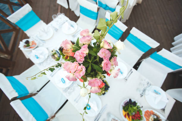 Beautifully decorated wooden table in a summer open-air cafe. Green branch and fresh flowers table decoration