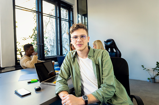 Portrait of young man sitting in office looking at camera.