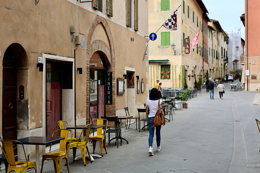 San Quirico d'Orcia, Province of Siena, Tuscany, Italy - 25 October 2022: Italian people go for a walk on the street of San Quirico d'Orcia. The city is a comune of about 2,500 inhabitants in the Province of Siena in the Italian region Tuscany, located about 80 kilometres southeast of Florence and about 35 kilometres southeast of Siena inside the Valdorcia landscape. It is named in honor of Saint Quiricus.