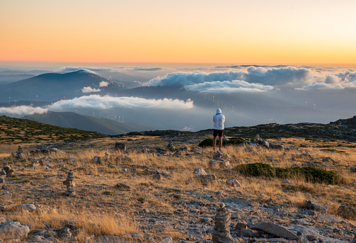 Serra da Estrela, Portugal - 08/18/2020: Sunset at the top of the Serra da Estrela Natural Park, Portugal with low clouds and a person observing the landscape