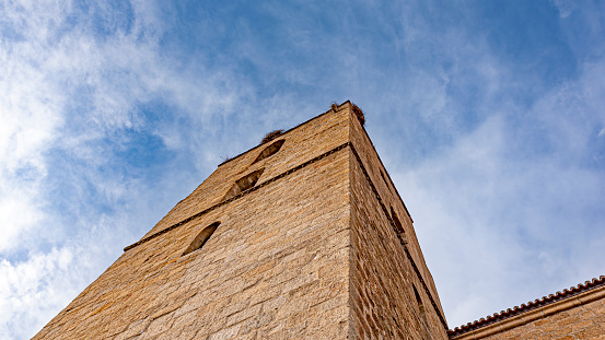 Avila, España - 03/11/2023: Part of old stone building in perspective with blue sky background at daytime