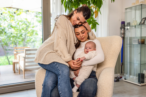 Loving lesbian couple spending time with their baby while at home.