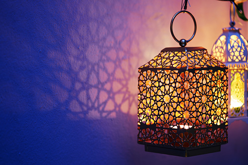 Arabic lantern with candle at night for Islamic holiday. Muslim holy month Ramadan. The end of Eid and Happy New Year. Copy space on dark background.