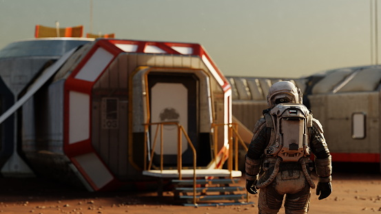 Astronaut stands before the entrance to a modular habitat on Mars, the beginning of a new era. 3d render