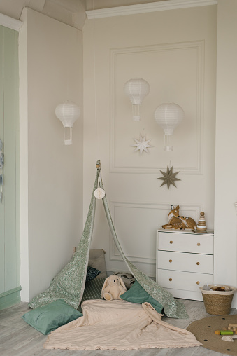 Children's tent tent with pillows and soft bunny toy, white chest of drawers in a modern room for small children
