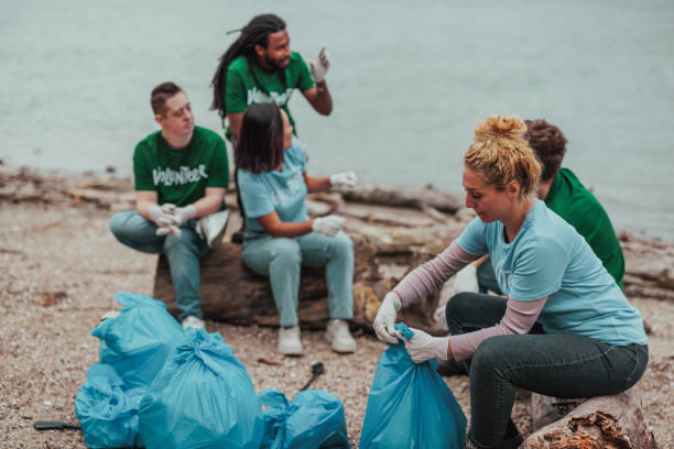 istock Five volunteers in uniforms sitting by the river sorting after collecting trash 2075926249