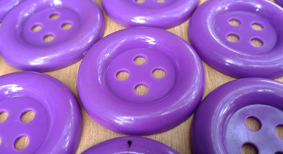 close up of purple sewing button on wooden table background with copy space