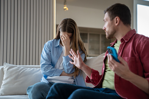 Upset woman, beside herself with stress in difficult relationship, listens to accusations, insults from abusive husband. Angry irritated man asks hysterical annoyed wife to stop talk in family quarrel