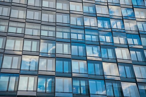 Glass exterior of contemporary building reflects blue cloudy sky, Modern city architecture