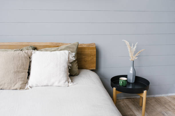 istock Black modern bedside table next to the double bed with grey bedding in a simple bedroom interior 2075965451