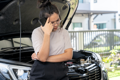 The young woman is worried about a broken-down car