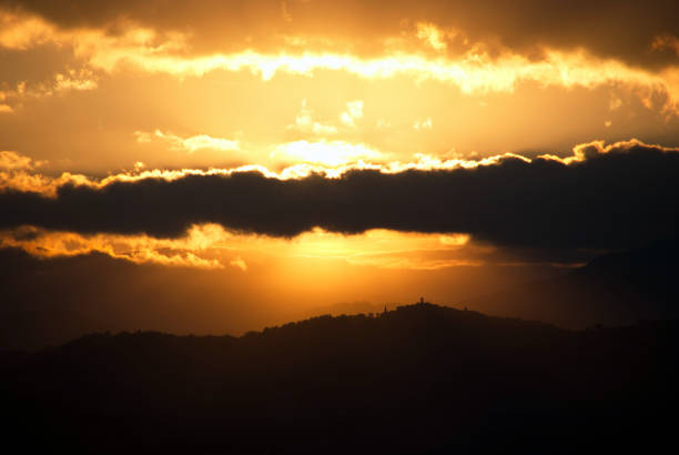 profile of a hill under a dark cloud in the sunset sky