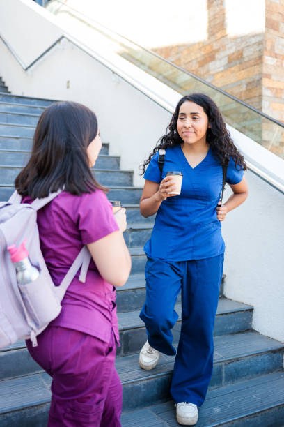 istock Two hispanic nurses relaxing and talking with coffee after work. Female Healthcare workers leaving clinical building 2075995468
