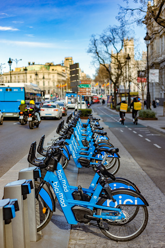 Madrid, Spain. Bicycle rental parking located on the bustling Alcalá Street in Madrid next to a bike lane.