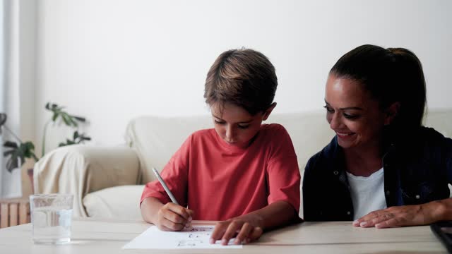 Mother and son doing homework at home living room. Mom help child boy for education in elementary school