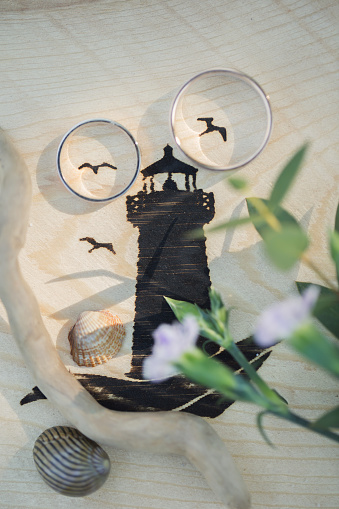 Two wedding rings in a picture with a lighthouse and seagulls.