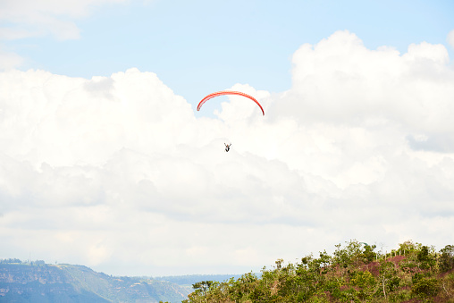 Extreme recreational activities: paragliding in the Chicamocha Canyon area, Santander, Colombia. Paraglider flying in the clouds over the Andes Mountains.