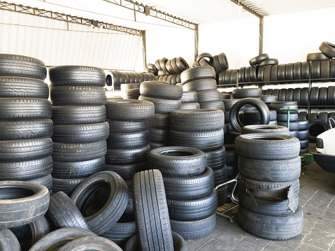 Photo taken in a tire store, with a pile of news and used tires.