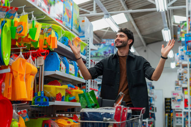 istock Latino man is inside a chain store with his shopping cart looking for important items he needs for the house 2076093005