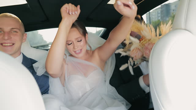 Exuberant Wedding Party Singing in Luxury Car, Bride and groom with best man singing and laughing in a luxury car.