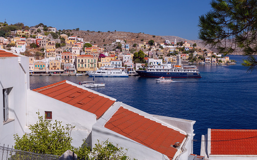 View of colorful traditional houses and fishing boats in the fishing village Symi on a sunny day. Greece. Dodecanese.
