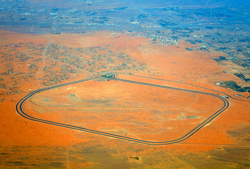 Jebel Mileina, Sharjah, UAE: aerial view of the camel race track in the desert - Al-Dhaid camel racing arena - Camel racing is a crucial part of Emirati culture, tracing back to its Bedouin roots. It’s a symbol of local culture and a tourist attraction. The sport is a key part of social celebrations and has economic significance, with camels historically used as a form of wealth and currency. Today, camel racing is a popular sport in the UAE, with camels treated like athletes in preparation for races. Overall, camel racing reflects the historical, social, and economic aspects of Emirati culture.