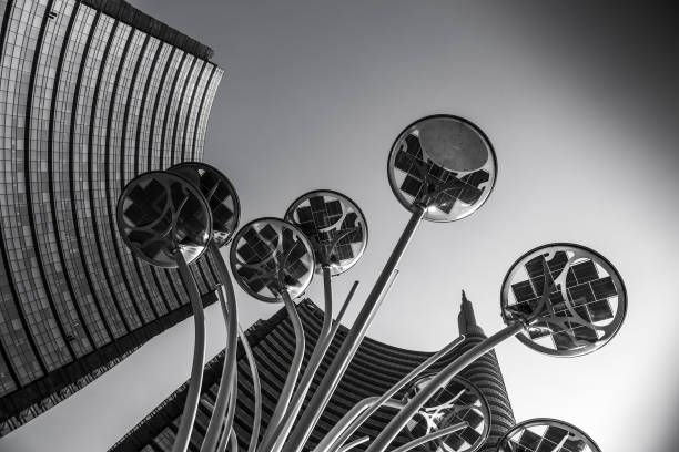 Palaces and skyscrapers in the 'porta nuova' district. This is a photograph taken in piazza gae aulenti in Milan. The subject of the shot is a lamp used to illuminate the square, taken from below. In the background are the skyscrapers facing the same square