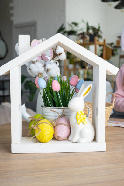 Tiny house of cozy home with Easter decor with rabbit and eggs on table of kitchen. Building, design, project, moving to new house, mortgage, insurance, rent and purchase real estate