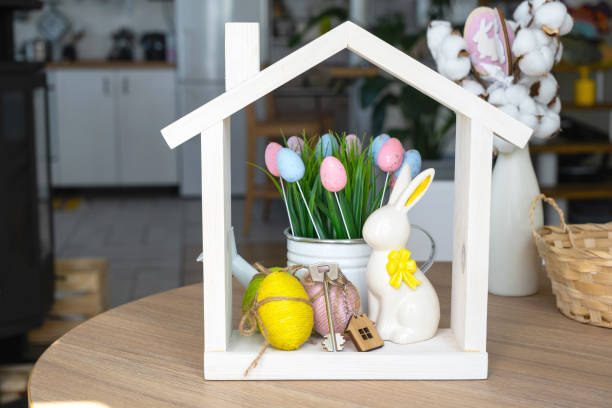 istock Key and tiny house of cozy home with Easter decor with rabbit and eggs on table of kitchen. Building, design, project, moving to new house, mortgage, insurance, rent and purchase real estate 2076140166