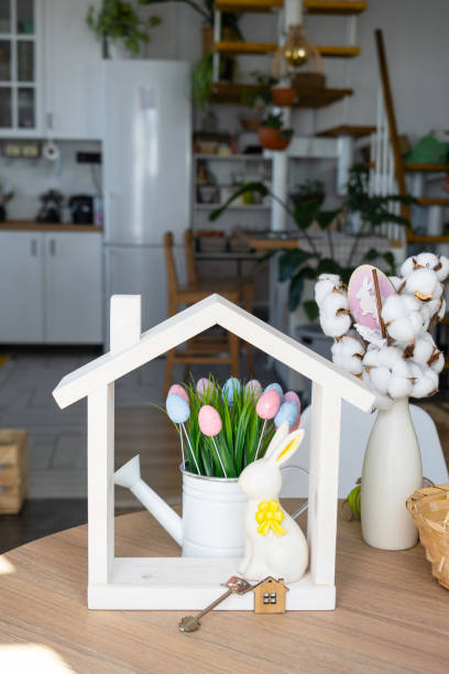 istock Key and tiny house of cozy home with Easter decor with rabbit and eggs on table of kitchen. Building, design, project, moving to new house, mortgage, insurance, rent and purchase real estate 2076140683