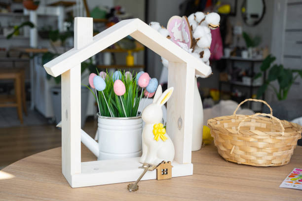 istock Key and tiny house of cozy home with Easter decor with rabbit and eggs on table of kitchen. Building, design, project, moving to new house, mortgage, insurance, rent and purchase real estate 2076140687