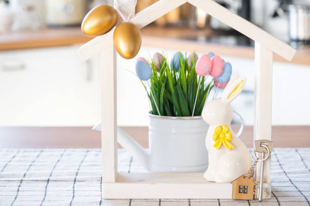 istock Key and tiny house of cozy home with Easter decor with rabbit and eggs on table of kitchen. Building, design, project, moving to new house, mortgage, insurance, rent and purchase real estate 2076150897