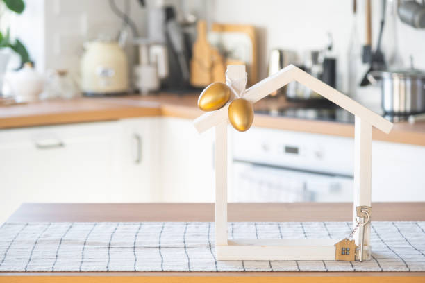 istock Key and tiny house of cozy home with Easter decor with color eggs on table of kitchen. Building, design, project, moving to new house, mortgage, insurance, rent and purchase real estate 2076150903