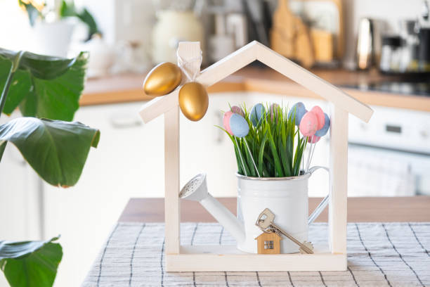 istock Key and tiny house of cozy home with Easter decor with color eggs on table of kitchen. Building, design, project, moving to new house, mortgage, insurance, rent and purchase real estate 2076150915