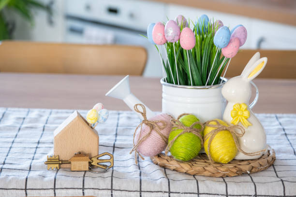 istock Key and tiny house of cozy home with Easter decor with rabbit and eggs on table of kitchen. Building, design, project, moving to new house, mortgage, insurance, rent and purchase real estate 2076150929