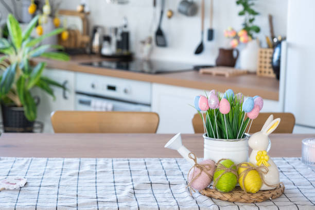 istock Easter decoration of colorful eggs in a basket and a rabbit on the kitchen table in a rustic style. Festive interior of a country house 2076150930