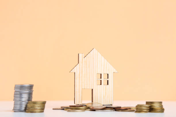istock Wooden house model with coins on beige background 2076152570
