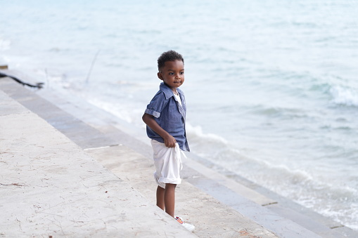 Beautiful young boy looking at the beach early in the morning.