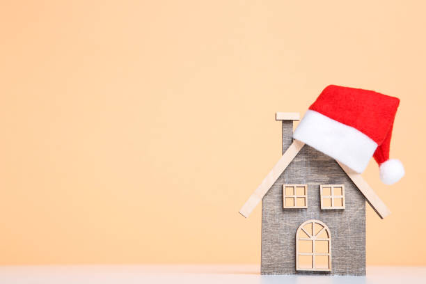 istock Wooden house model with santa hat on beige background 2076165701