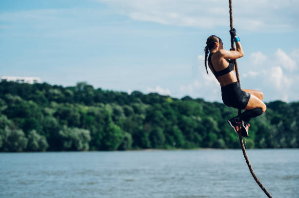 istock Strong woman climbing a rope while participating in an obstacle course race 2076167884