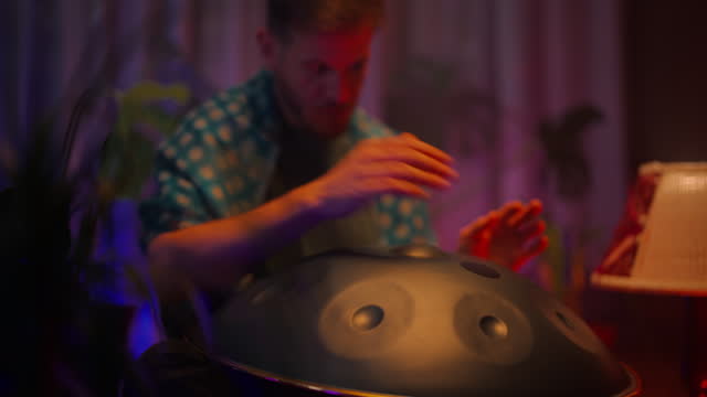 Man sitting on ground and playing handpan