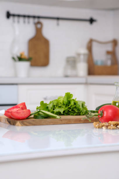 istock Cutting fresh tomatoes, cucumbers, green salad, nuts, oil at table in a light kitchen, closeup 2076217842