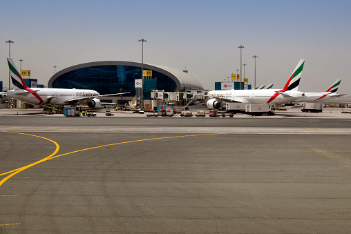Al Garhoud district, Dubai: Dubai International Airport, apron of terminal 3 - Several Emirates Boeing 777 aircraft at gate positions. Futuristic glass and steel façade, the terminal was designed by Aéroports de Paris (ADPi) as the hub for Emirates.