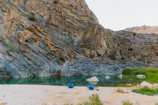 Scenic view of two blue kayak boats by the river hidden in the picturesque canyon in the mountains of Oman, Middle East