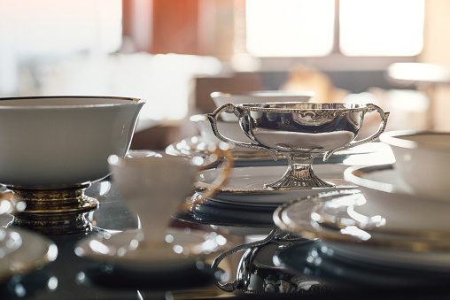 Silver or silver plated tea pot, sugar bowl and cream or milk jug. Ornamental silverware to serve hot tea or coffee. Selective focus.