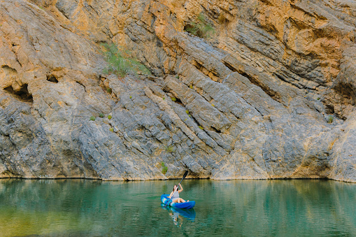 Female traveler kayaking in the river hidden In the picturesque canyon in Oman